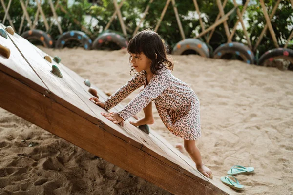 Portrait d'une vue de côté une petite fille commencer à essayer de monter sur la planche de bois montée — Photo