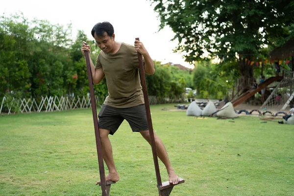 Portret młodego mężczyzny Azjatycka próbuje równowaga stojący z drewnianych palach — Zdjęcie stockowe