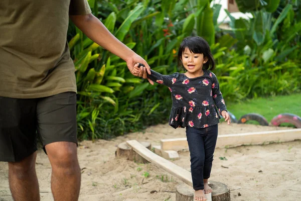 Eine Tochter, die vom Vater mit Händchenhalten auf der Suche nach dem Gleichgewicht unterstützt wird — Stockfoto