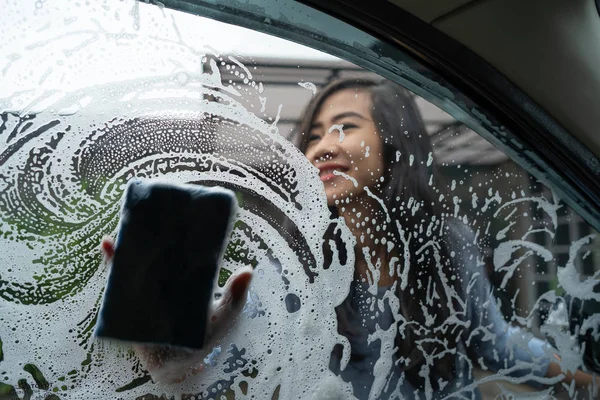 woman wash her car window with soap