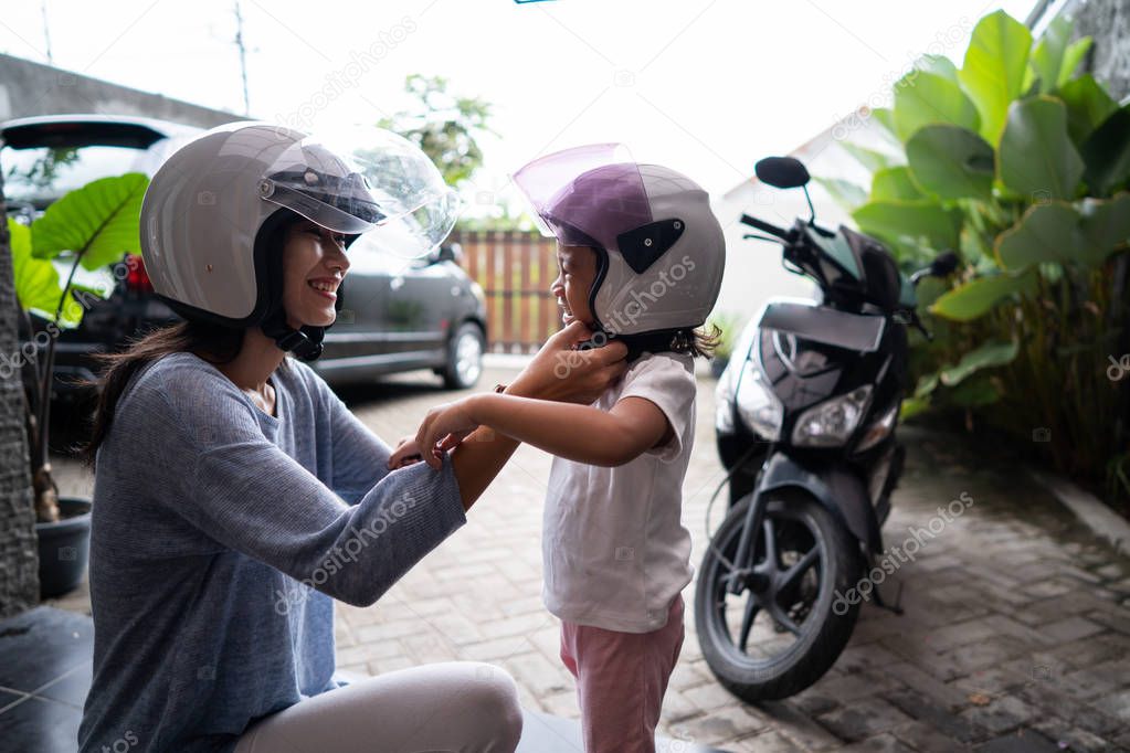 mom helped her daughter to put on helmet