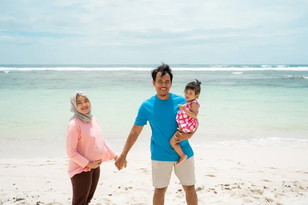 Pregnant wife with husband and his daughter on the beach hold hands — Stock Photo, Image