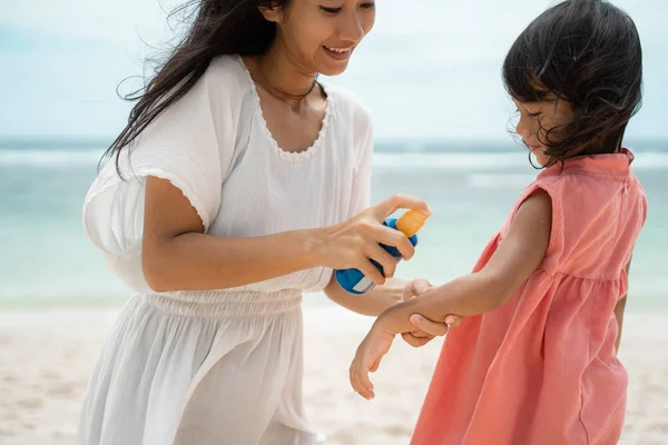 Alkalmazás sunblock lánya bőr előtt játszik a tengerparton — Stock Fotó