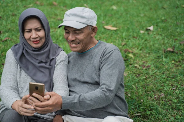 Vedoucí muslimský pár společně pomocí smartphone v parku — Stock fotografie