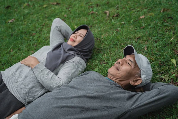 Pasangan senior muslim asia berbaring di atas rumput — Stok Foto