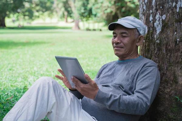 senior old man using tablet pc in the park