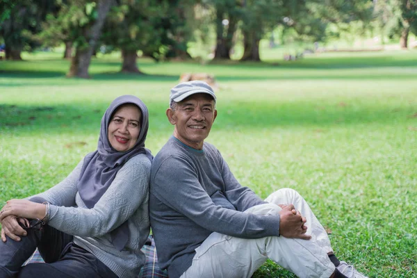 Para Senior siedzący na powrót podczas relaksu w parku — Zdjęcie stockowe