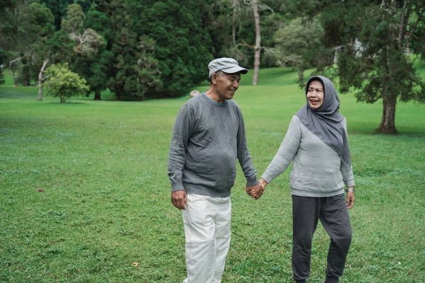 庭で一緒に歩いているイスラム教徒のシニア カップル — ストック写真