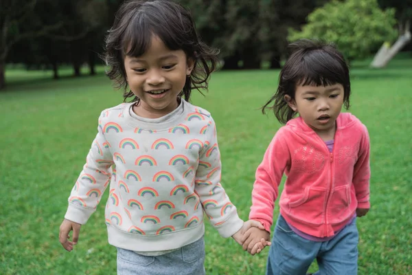 Chicas jóvenes corriendo juntas y cogidas de la mano en el parque — Foto de Stock