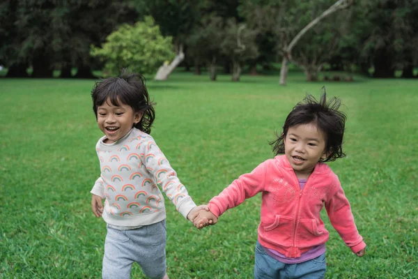 Meninas correndo juntos e de mãos dadas no parque — Fotografia de Stock