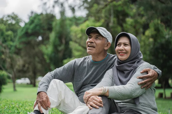 Anciano maduro y mujer sentado en una hierba en el parque — Foto de Stock