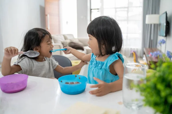 Adik perempuan makan satu sama lain sambil sarapan — Stok Foto