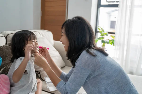 Азіатська мати обличчя малює свою маленьку дочку — стокове фото