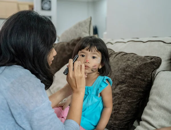 Азиатская мать лицо живописи ее маленькая дочь — стоковое фото