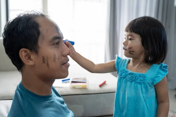 daughter painting on her dads face