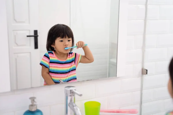 Asiático niña cepillos su dientes solo en el cuarto de baño —  Fotos de Stock