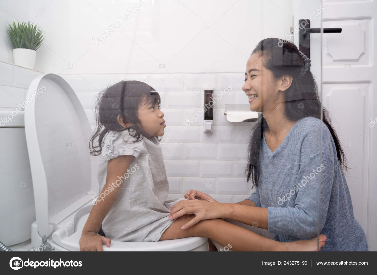 Daughter peeing Mother help her daughter to sit on the toilet — Stock Photo © odua  #243275190