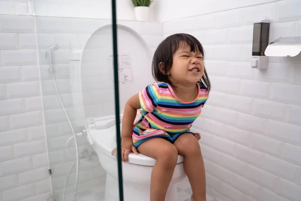 Азиатский ребенок нажать его трудно, сидя на унитазе — стоковое фото