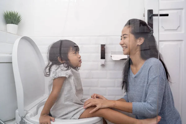 Matka pomóc jej córka siedzieć w toalecie — Zdjęcie stockowe