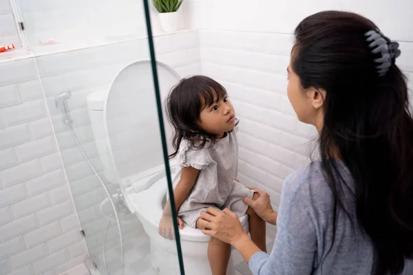 Мать помогает своему ребенку пользоваться туалетом — стоковое фото