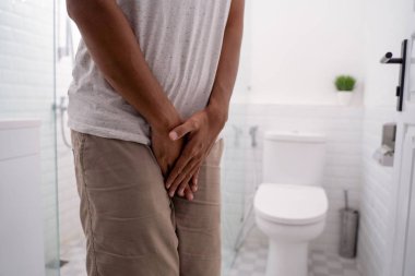 man hold his genitals in the toilet before peeing clipart