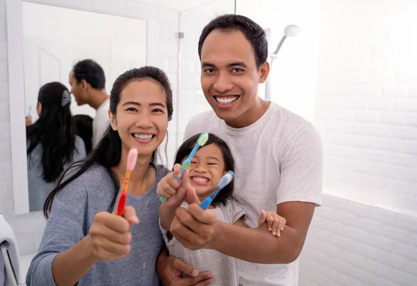 Ather e mãe com criança mostrando sua escova de dentes — Fotografia de Stock