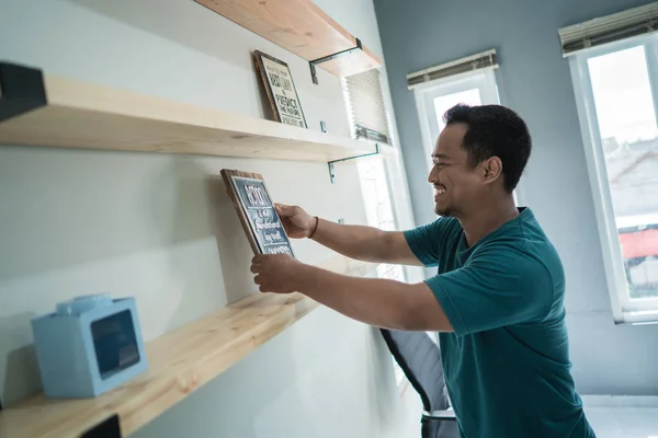 Porträt eines lächelnden jungen Arbeiters beim Arrangieren der Wanddekoration — Stockfoto