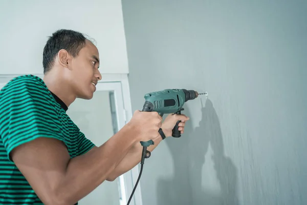 Porträt eines jungen Mannes mit einem Bohrer an der Wand — Stockfoto