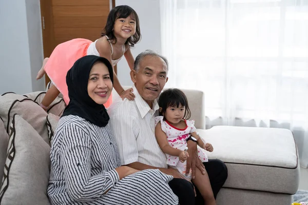 Glückliche asiatische muslimische Großeltern mit ihren Enkeln zu Hause — Stockfoto