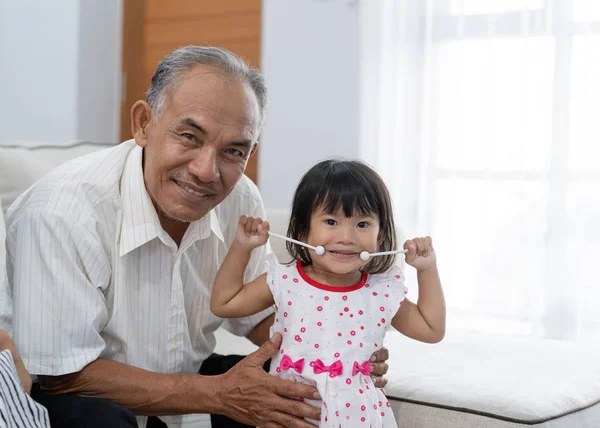 La unión de un abuelo con su pequeña princesa sosteniendo el instrumento de música mira a la cámara —  Fotos de Stock