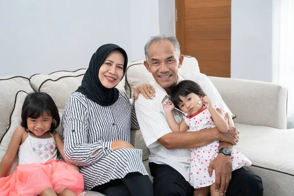 Счастливые азиатские мусульманские бабушка и дедушка с внуками дома — стоковое фото