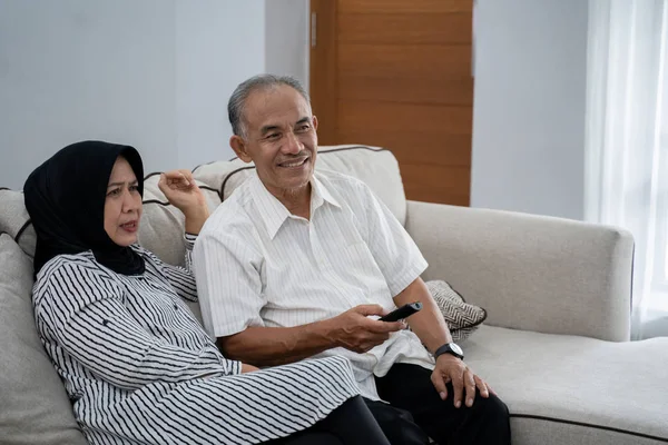 Pasangan muslim asia duduk sofa matang santai ketika menikmati televisi — Stok Foto