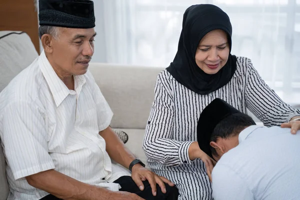 Homem ajoelhado e beijar seus pais mão pedindo perdão — Fotografia de Stock