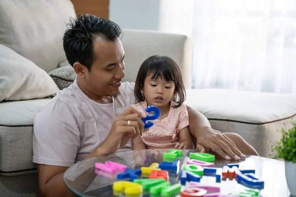 Retrato de un padre paciente enseña el alfabeto a su hija jugando juguetes de texto de colores —  Fotos de Stock