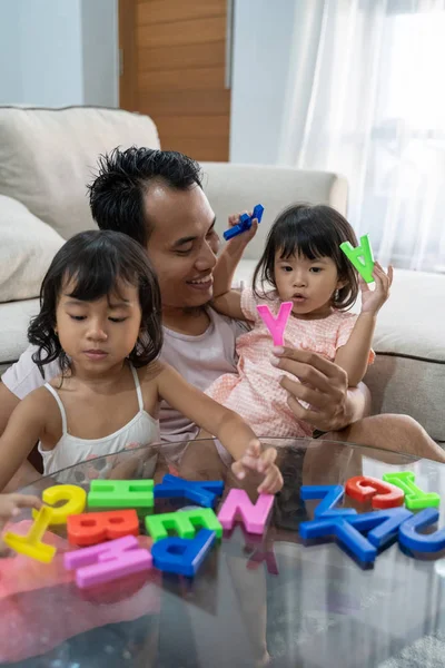 Retrato do pai união e suas duas filhas jogando texto alfabeto colorido — Fotografia de Stock