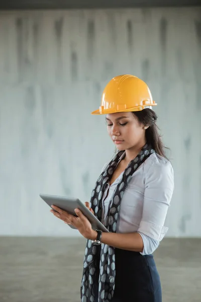 Business woman with hardhat using tablet pc in the project site — стоковое фото