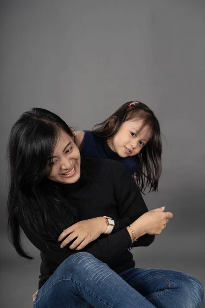 Mom and kid smiling over grey background — Stock Photo, Image