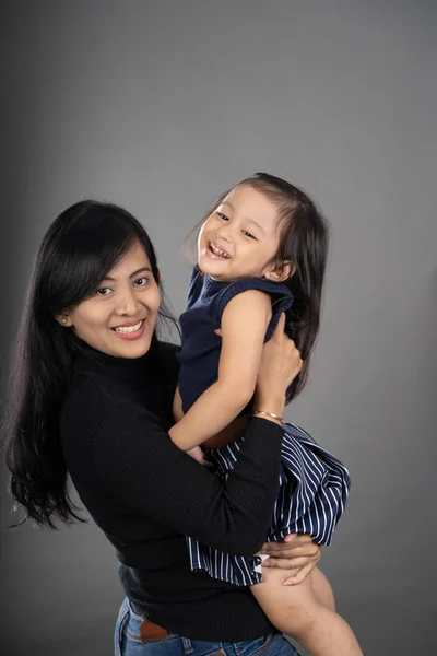 Mãe e criança sorrindo sobre fundo cinza — Fotografia de Stock