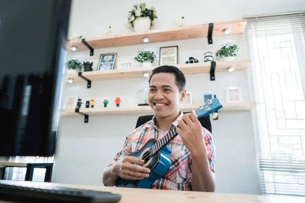 Mann spielt Gitarre und lächelt in seinem Büro — Stockfoto