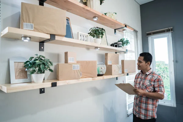 Asiático trabajador mirar el cajas en un madera estante en el oficina habitación — Foto de Stock