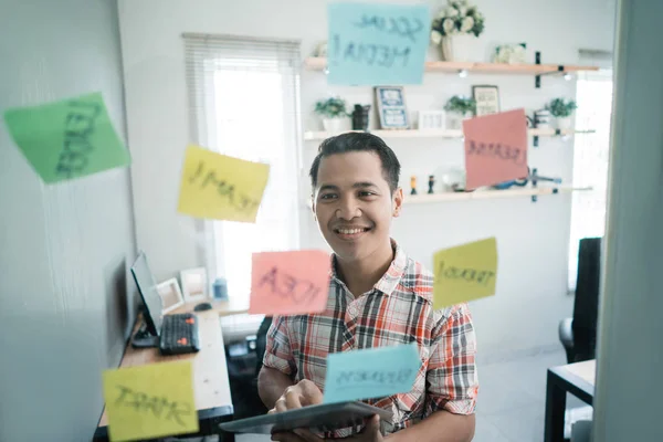 Pracovník muže podívat se na některé poznámky držet papír na skleněné stěny — Stock fotografie