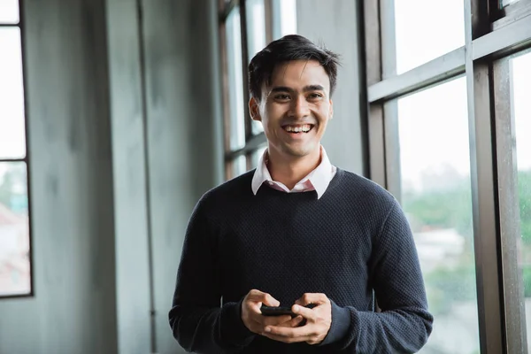 Asiático jovem homem sorrindo segurar um smartphone — Fotografia de Stock