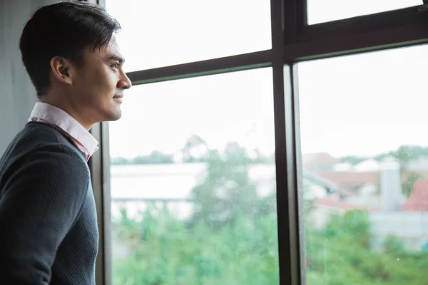 Азіатський молодий чоловік дивиться у вікна — стокове фото