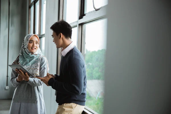 coworker discussion near the windows with tablet