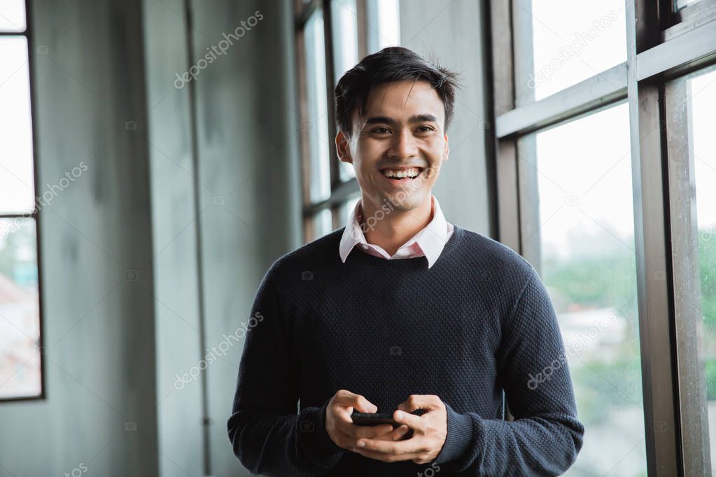 asian young man smiling hold a smartphone