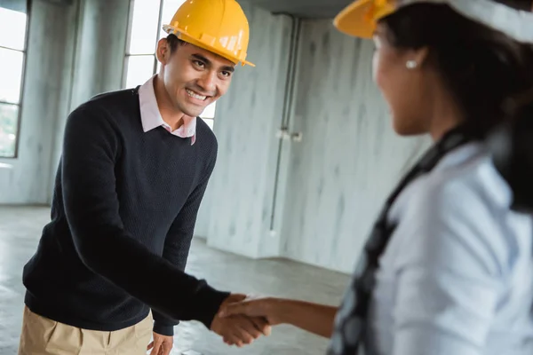 Hombre con hardhat estrechando la mano con su pareja — Foto de Stock