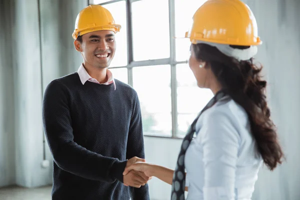 Hombre con hardhat estrechando la mano con su pareja —  Fotos de Stock