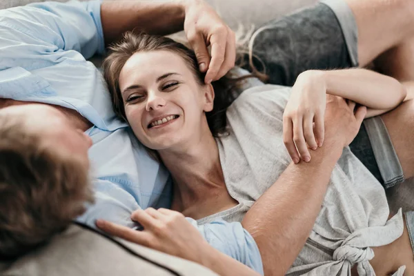 Casal de ligação e sorrindo enquanto deitado — Fotografia de Stock
