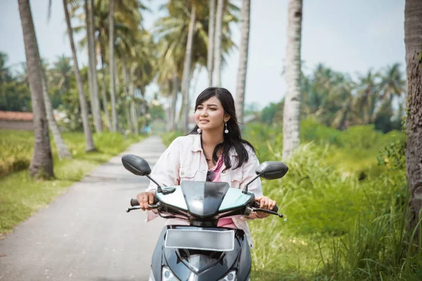 Donna in sella al suo scooter in strada di campagna tropicale — Foto Stock