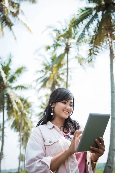 코코넛 나무 아래에서 태블릿 pc를 사용 하 여 아시아 여자 — 스톡 사진